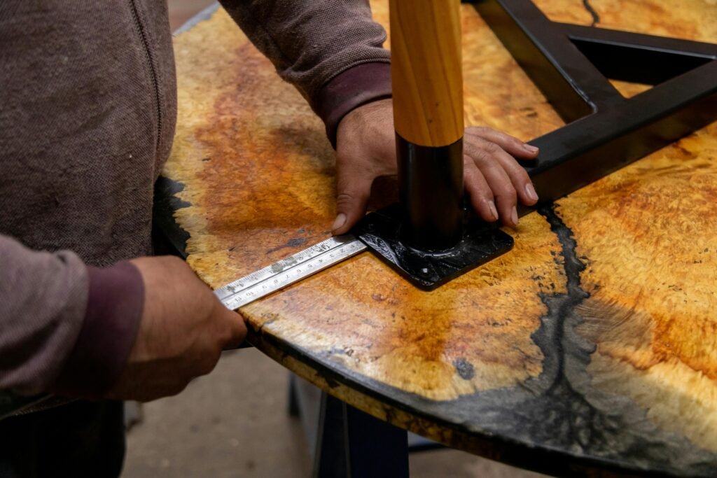pexels-photo-15060424-15060424 Craftsman measuring wooden table with ruler in workshop.