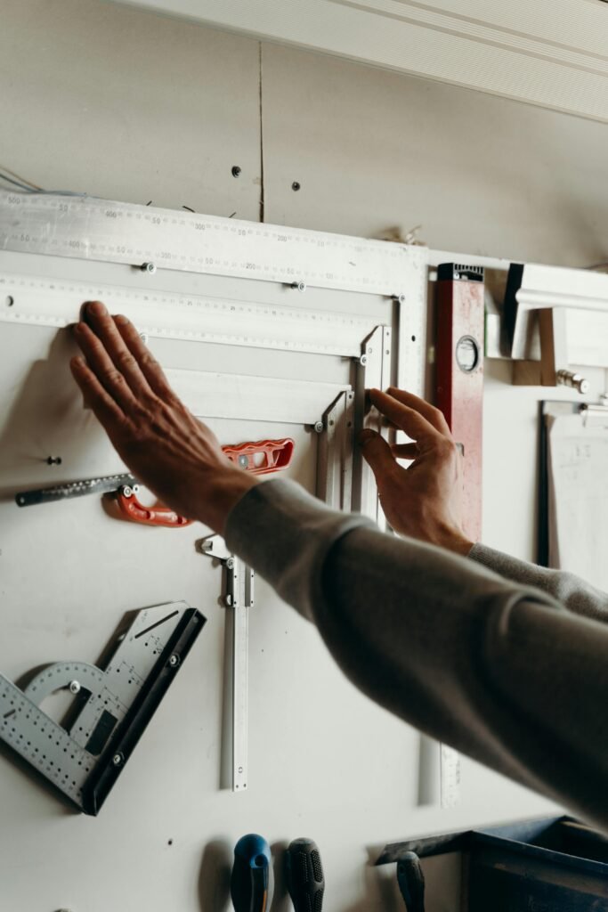 pexels-photo-7484805-7484805 Hands using measuring tools on a wall in a workshop setting. Perfect for carpentry concept.